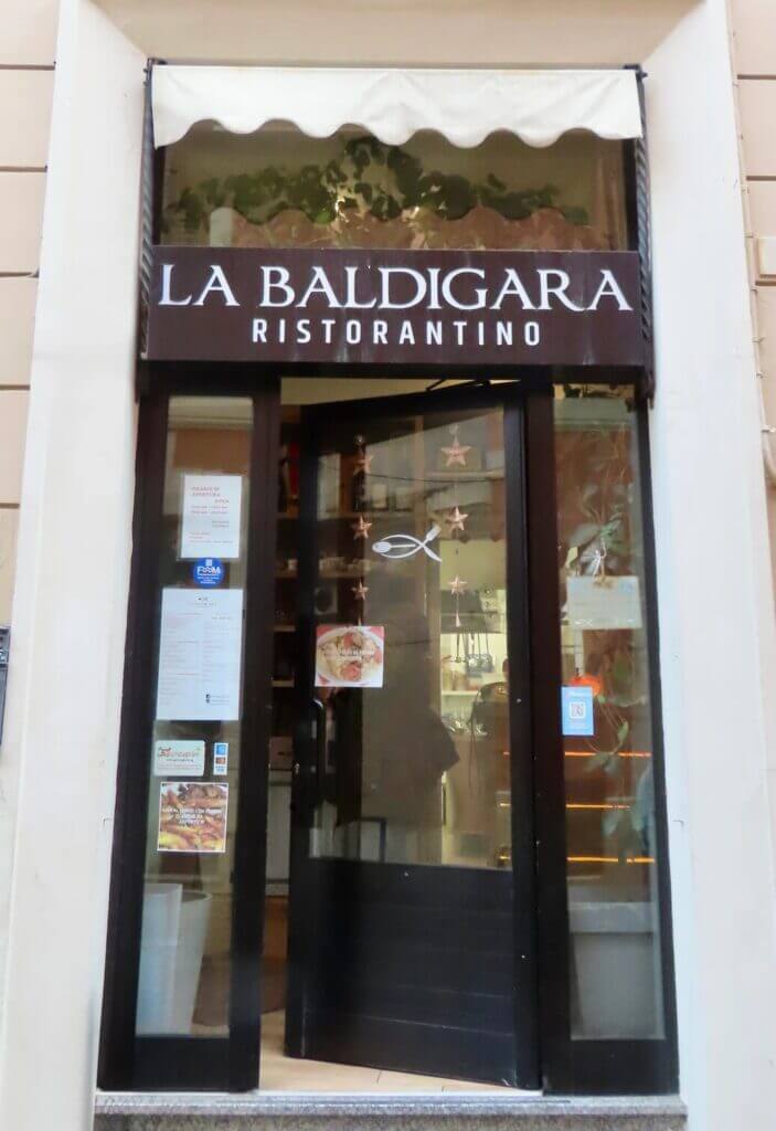 Entrance to La Baldigara Ristorantino, featuring glass doors and a sign with the restaurant's name.