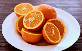 A white plate with several oranges cut in half.