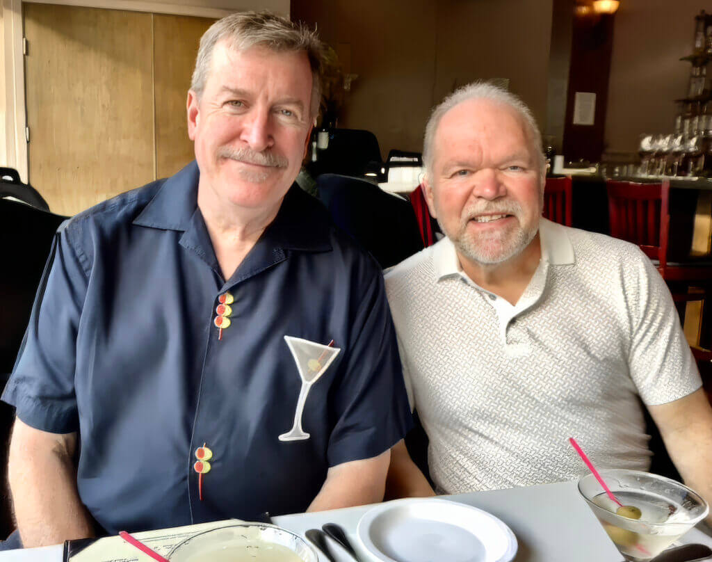 Two men smiling at a restaurant table with martinis