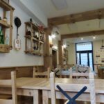 Interior of La Baldigara restaurant with rustic wooden tables and shelves displaying decorative items.