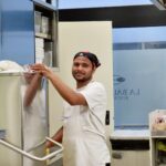 Staff member at La Baldigara restaurant working in the kitchen, wearing a bandana and apron.
